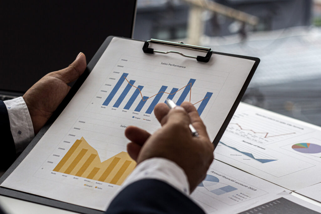 GV Compta - Un professionnel tenant un rapport financier dans ses mains, avec des graphiques et des données visibles. L'image illustre les services de comptabilité et d'analyse financière, mettant en avant l'accompagnement personnalisé et la gestion des finances.